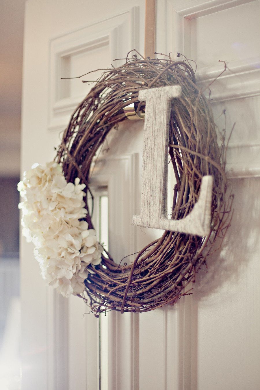 Use a grapevine wreath with sweet white flowers and a white washed initial for a