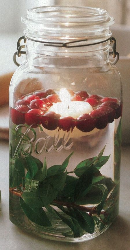 Christmas mason jar decoration: Leaves, cranberries, and a floating candle.