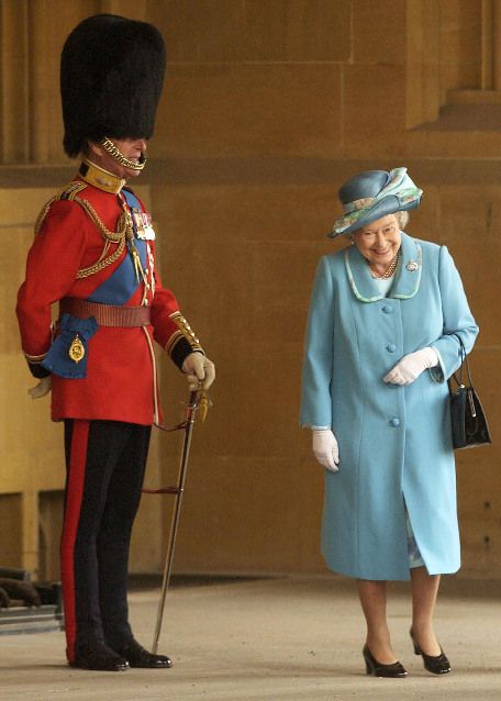 The Queen laughing as she passes her husband, The Duke Of Edinburgh in uniform..