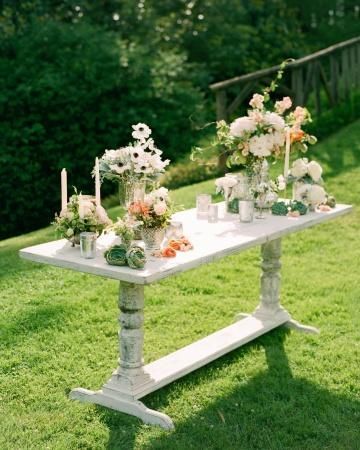 A distressed farm table topped with mercury glass, candles, ornamental peaches,