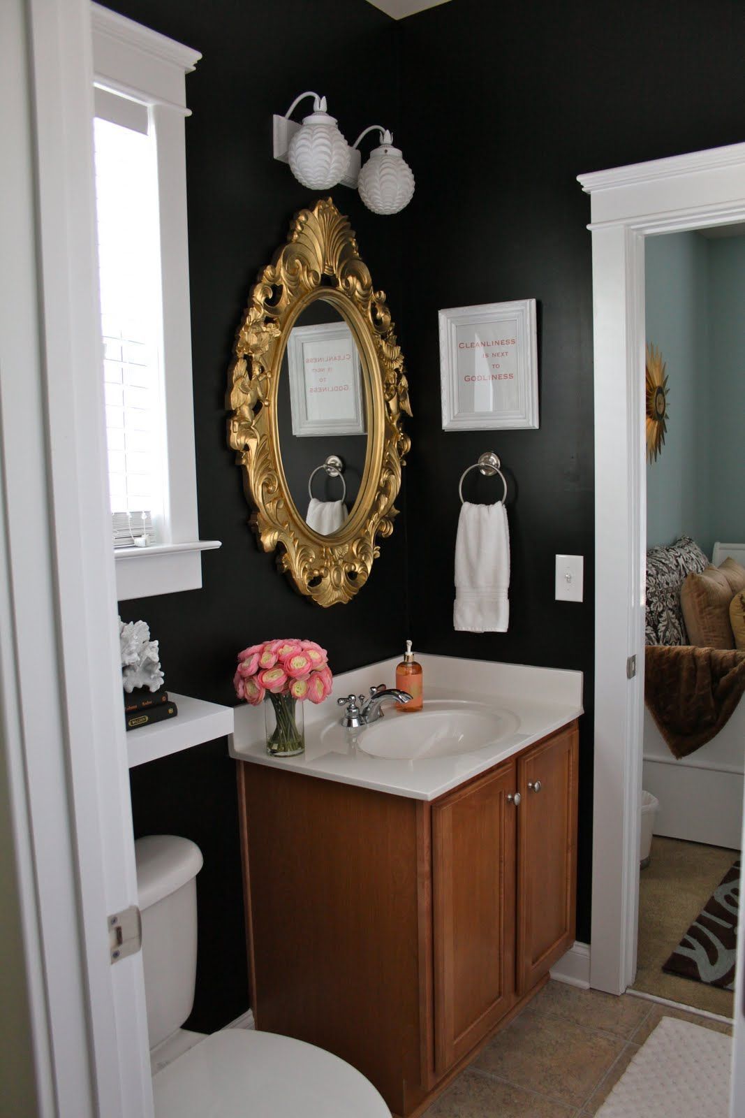 Black walls in the bathroom with gold framed mirror