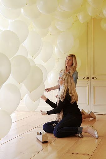 Tape the strings at various heights to create a wall of balloons.  Instant backd