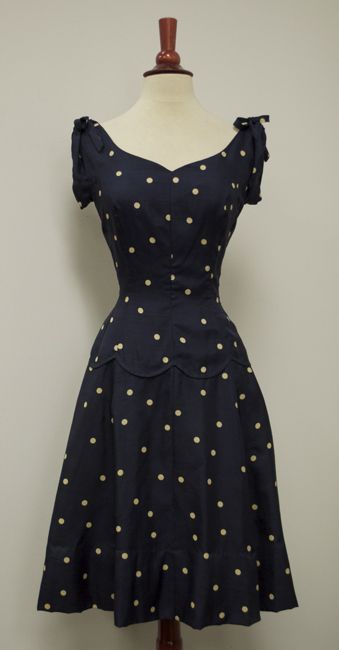 Navy silk polka-dot dress, c. 1940s. From the sweetheart of a neckline, the bodice is made even cuter with the gathers and bows at the shoulders. Fashioned with princess seams that cinch in, the
