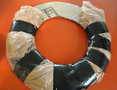Use plastic bags, cardboard, and duct tape to create your own wreath frame. Gives it that needed shape (roundness) then just wrap
