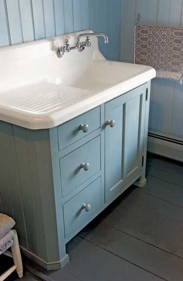 An old kitchen sink makes a nice bath lavatory atop a country cabinet by Crown Point Cabinetry.