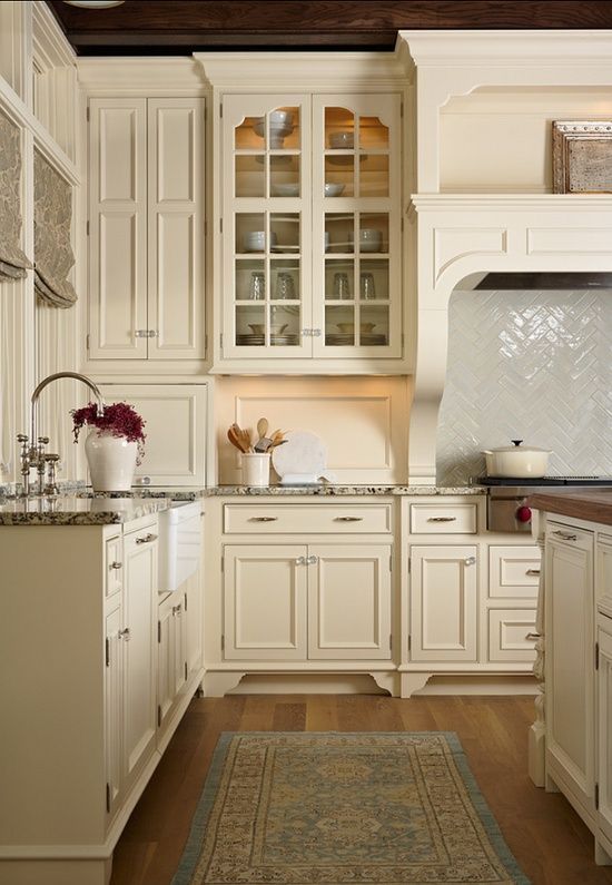 This creamy white country kitchen caught my eye, love the warm wood floors & the herringbone pattern above the range …