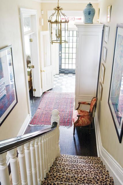 This entry way is warm and inviting. The checkerboard floor and door are gorgeous. I particularly love the red rug and the
