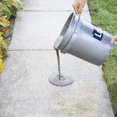 pouring the resurfacer onto the concrete walkway with a 5-gallon bucket