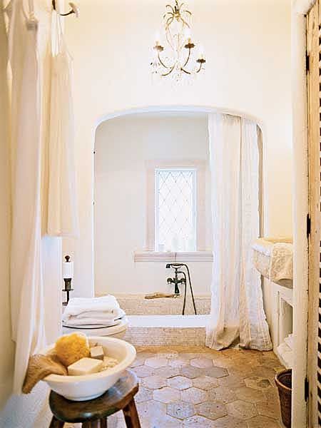 An original sunken, tiled tub anchors the bath, and floor tiles salvaged from a European villa accentuate the old-world feel.Love