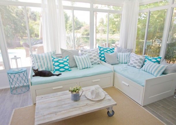 Ikea daybeds, a spraypainted end table (Valspar Exotic Sea), faux-wood tile, and such cute pillows! Love this sunroom makeover.