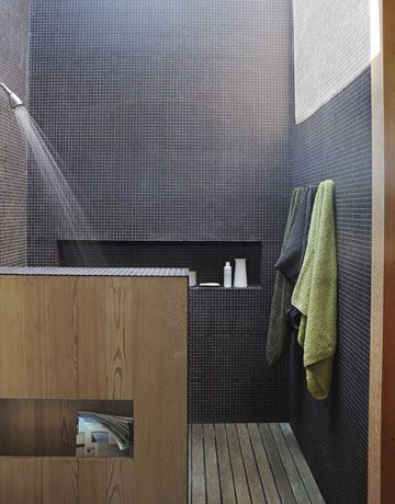In the master-bath shower, the walls are clad in black porcelain tiles that soar up to a wall-to-wall skylight.