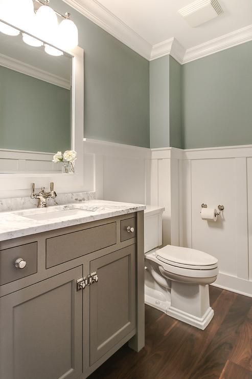 Tranquil bathroom features upper walls painted gray green and lower walls clad in board and batten lined with a creamy gray