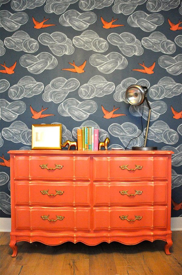 Vivid orange dresser against the backdrop of a very imaginative wallpaper