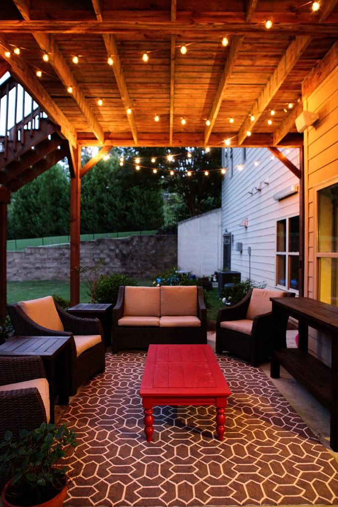 Idea for under deck outdoor patio at new house (2 outdoor rugs put together to make big rug and Christmas lights)–gorgeous