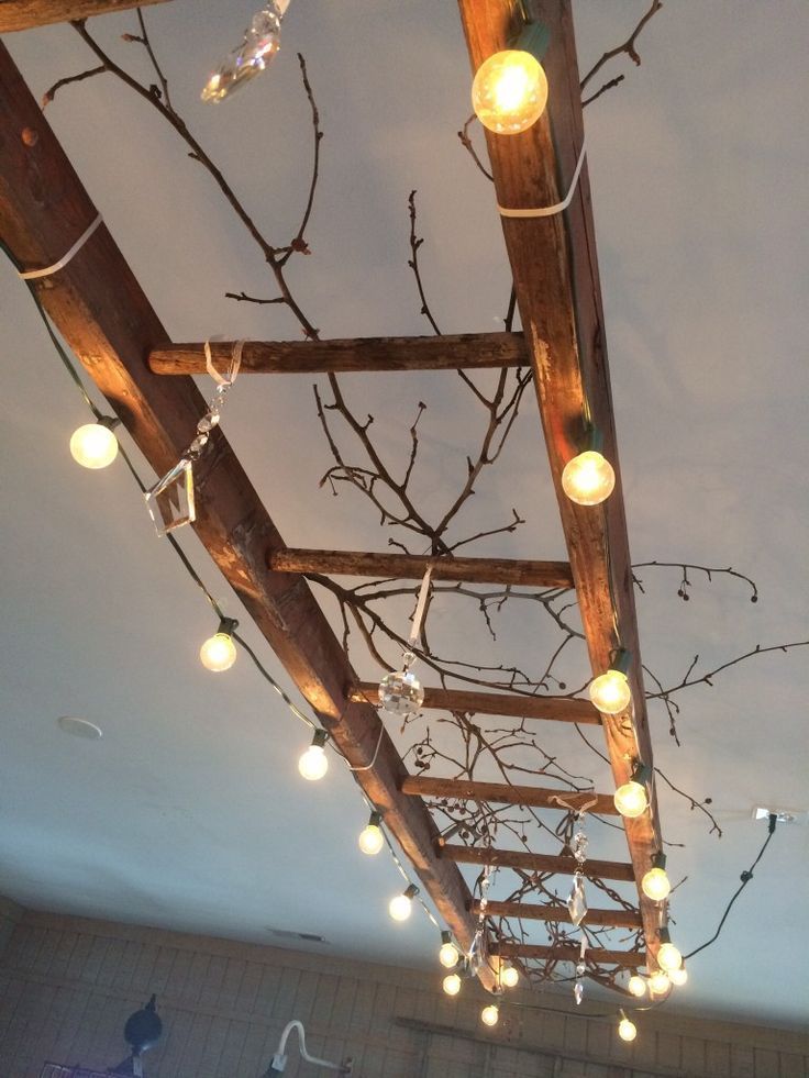 A vintage wooden ladder makes great lighting! This one is wrapped with globe lights, and decorated with vintage chandelier