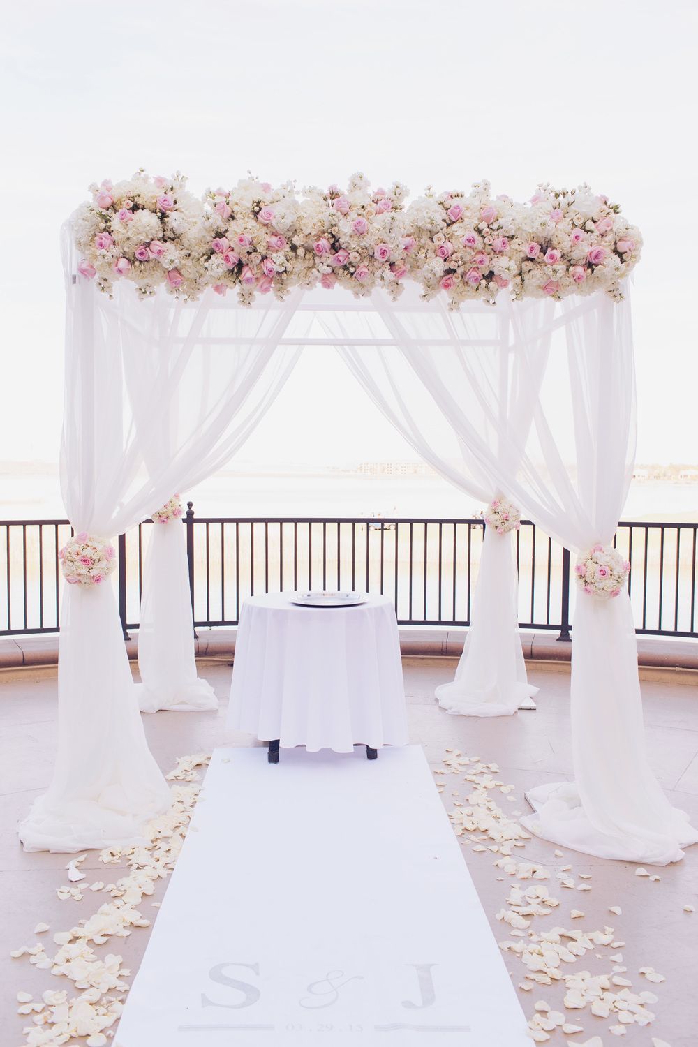 For the lakeside ceremony we dressed a chuppah in flowing ivory fabric topped with ivory and pale pink roses.  Matching topiaries