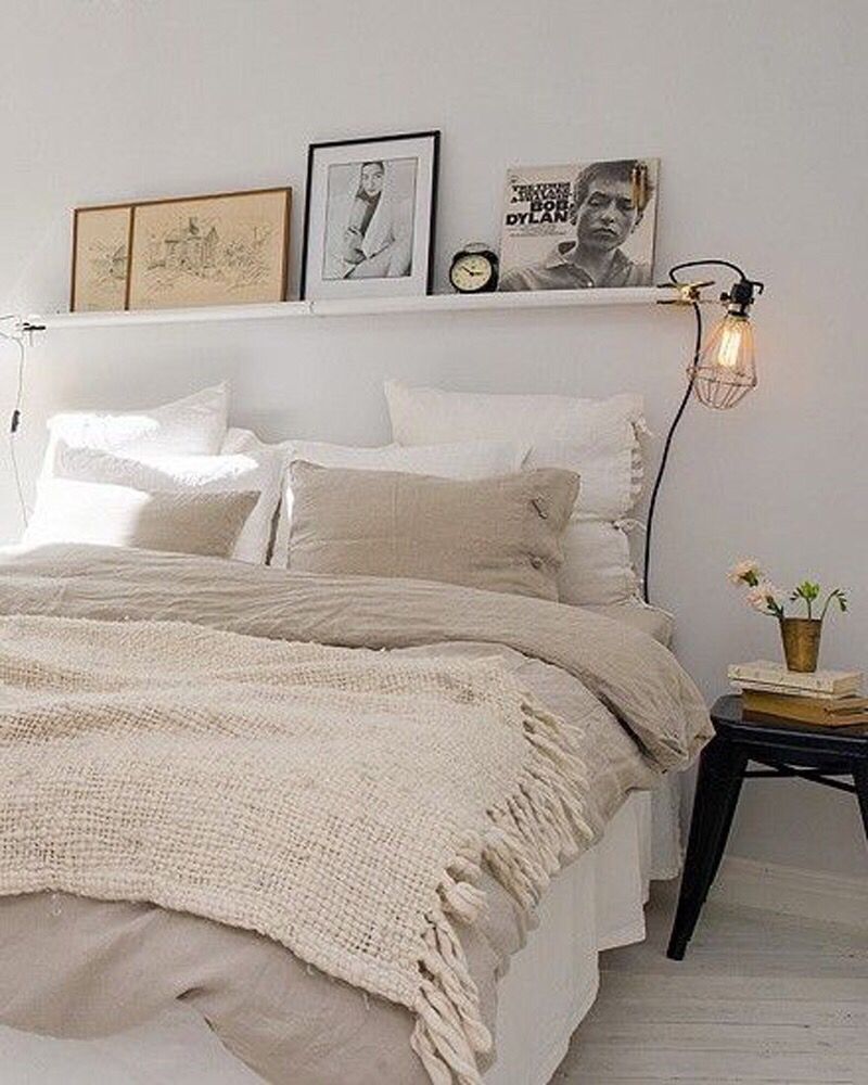 Simple white bedroom, soft lighting and personalised art along the shelving.