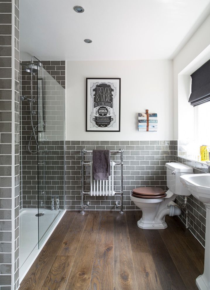 Traditional bathroom with dark rustic wood floors, gray subway tile, glass walk-in shower and white pe