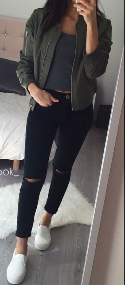 Hunter green bomber jacket with gold zippers, plain dark grey crop top, black ripped skinny jeans.