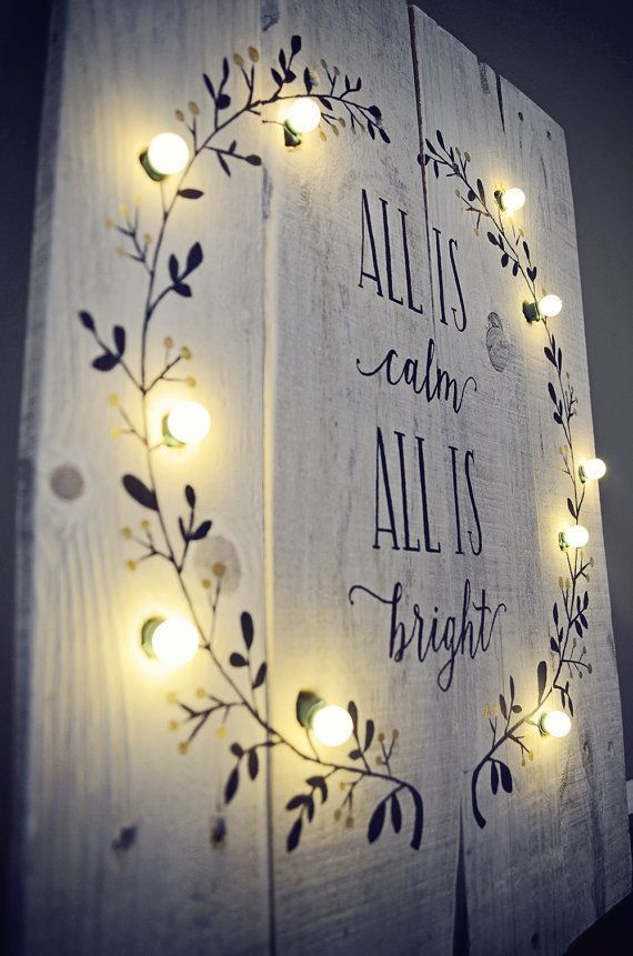 This hand-painted All is Calm All is Bright sign with lighted wreath on whitewashe