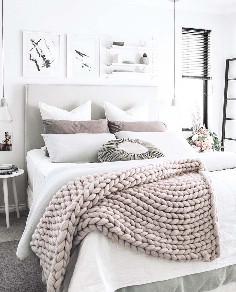 A chunky knit wool throw adds texture and interest to a gray and white bedroom.