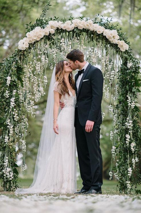 A lovely arbor with hanging flowers and a row of white rosebuds looks absolutely e