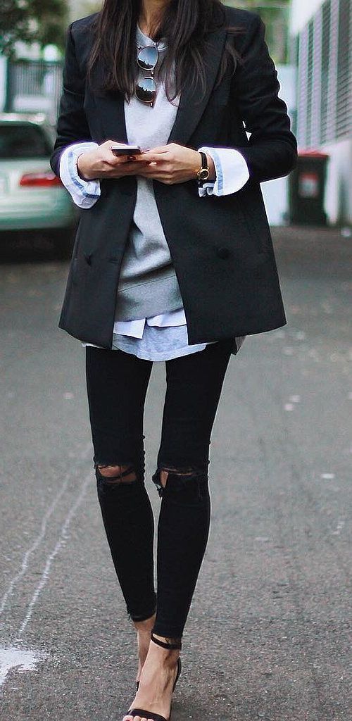 Ripped jeans paired with a sweatshirt layered under a classic blazer
