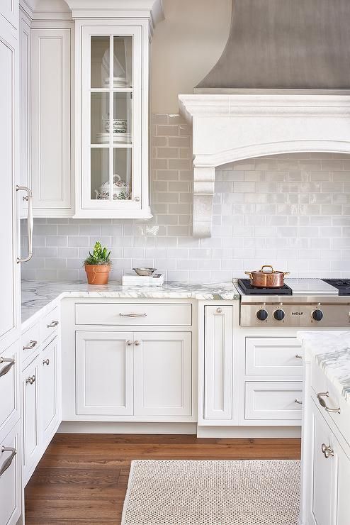 White and gray kitchen features a zinc French kitchen hood with corbels stands over a gray mini subway tile backsplash and an