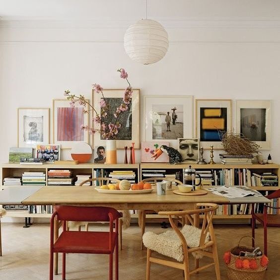 Dining room with low bookcase, vintage art, mismatched chairs