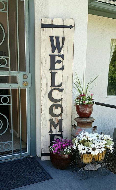 Welcome sign. Cedar boards, sanded, paint, sand to distress, then stain. Add painted wooden letters of choice and iron brackets