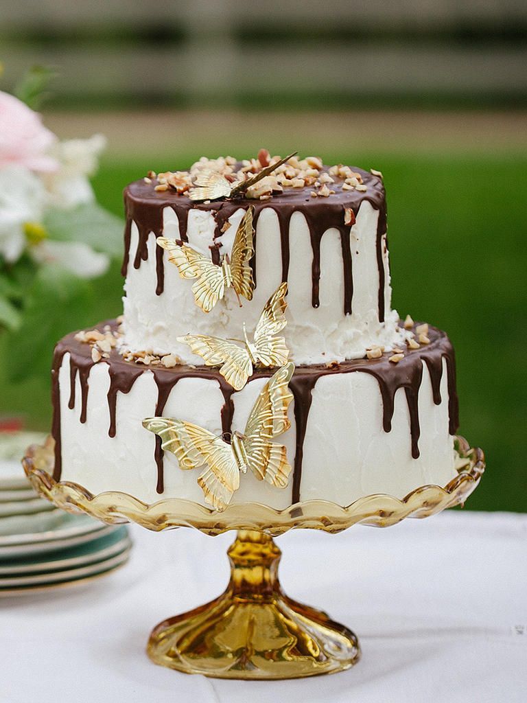 Wow your guests with a whimsical wedding cake thats delicately designed with a chocolate drizzle drip and gilded gold butterflies.