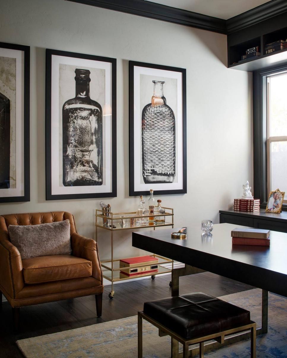 A glass-and-gold bar cart, brown leather armchair and oversized artwork of glass bottles give Mad Men-esque flair to this home