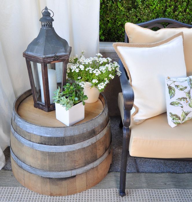 Front porch decor: half-whiskey barrel table, Lantern, flowers pulled, curtain = inviting.