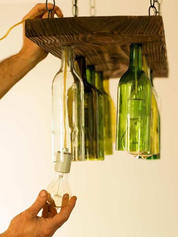 How To Make a Chandelier From Old Wine Bottles: Suspend bottle-holding plank from ceiling canopy with chain. Use caulk gun to add