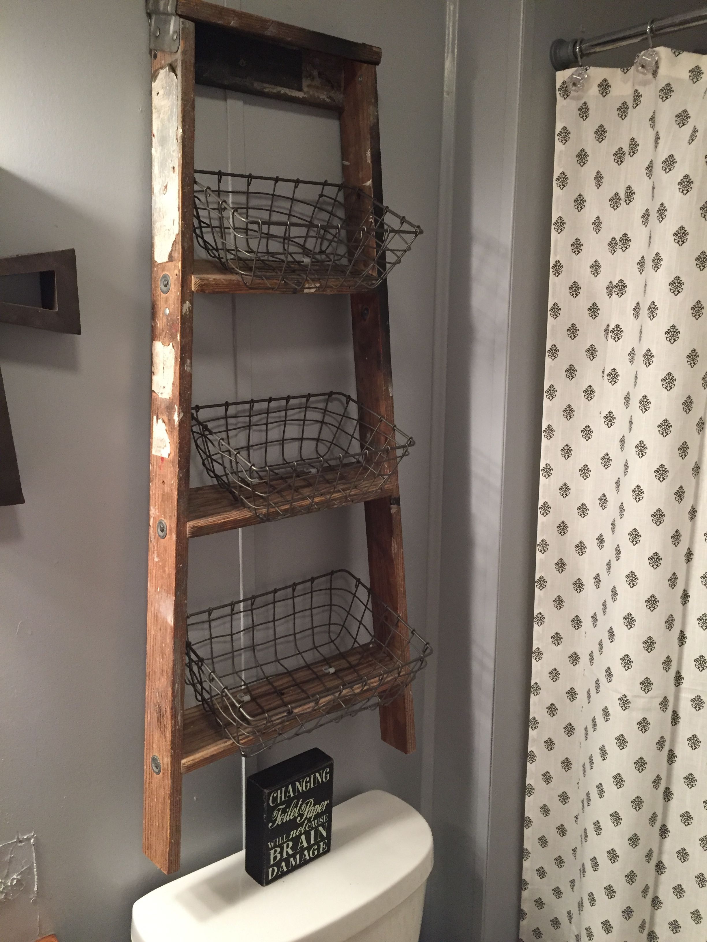 Old ladder turned into above bathroom storage!! I got a ladder out of the garbage bought some wire baskets and boom amazing