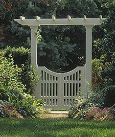 The double-door gate has a scooped top edge and hangs from square posts that support an overhead arbor.