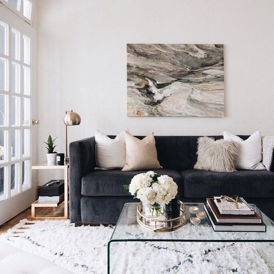 Coordinated colours, dark blue/grey couch, white, beige and generally neutral textiles and rug