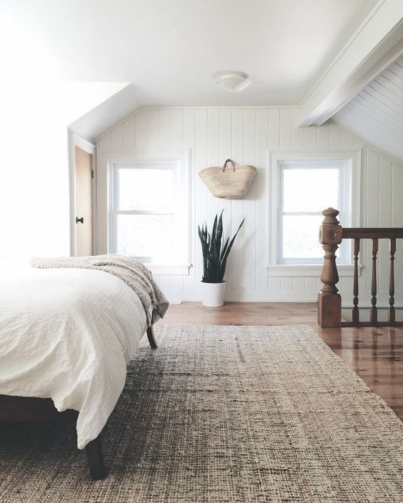 simple, minimalist bedroom with snake plant, white bedding, and natural jute rug.