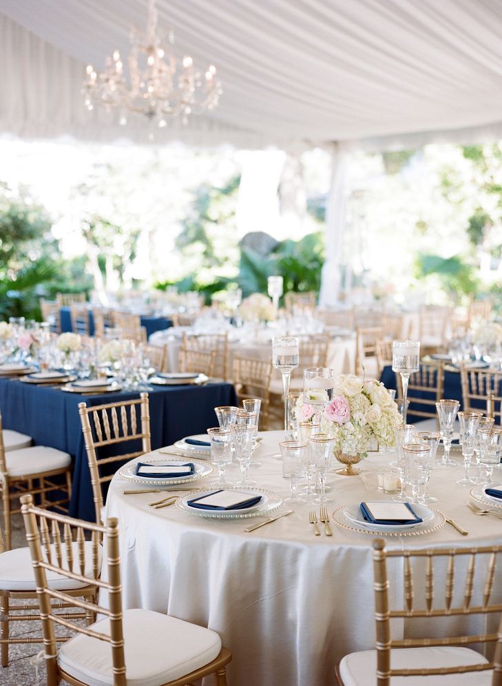 Polished navy, gold, and blush reception with cream settings with navy napkins, gold touches, and blush flowers in the centerpiece