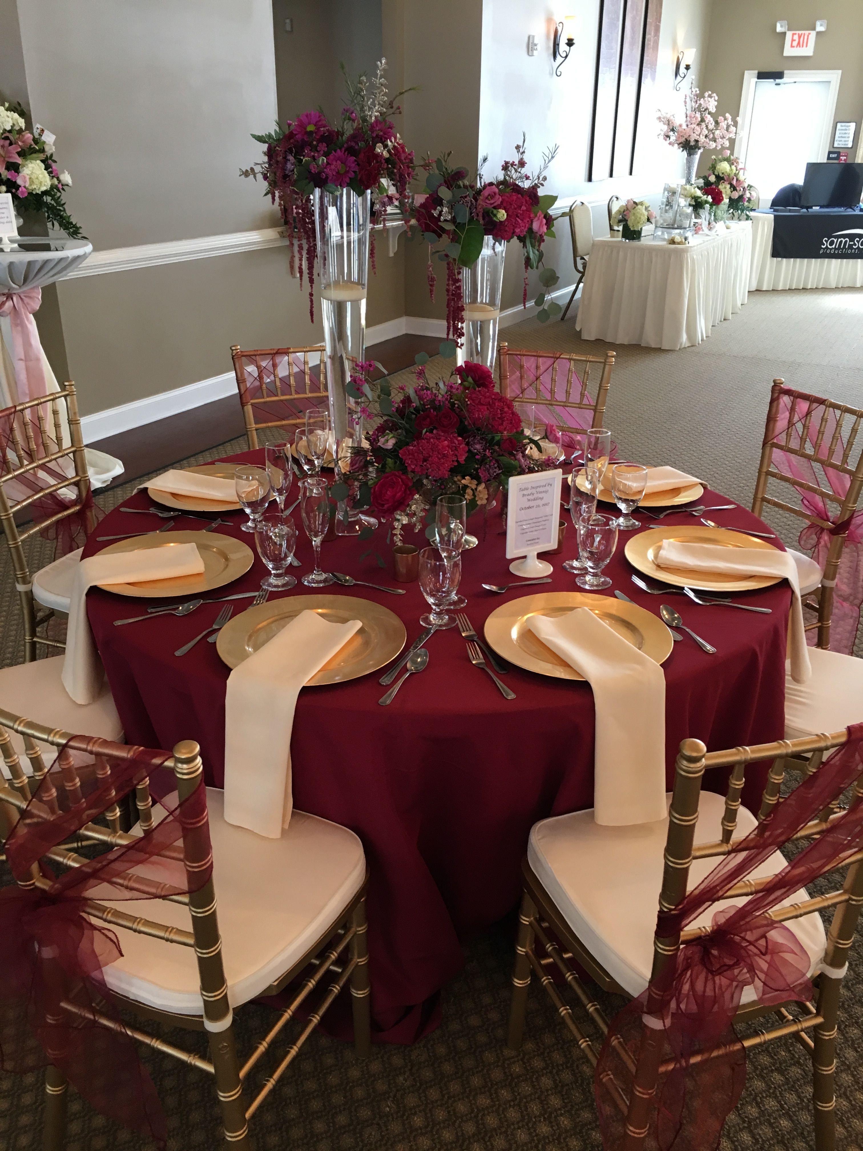 This gorgeous table set up is filled with upgrades!  Floor length Burgundy table cloth, champagne napkins, gold charger plates,