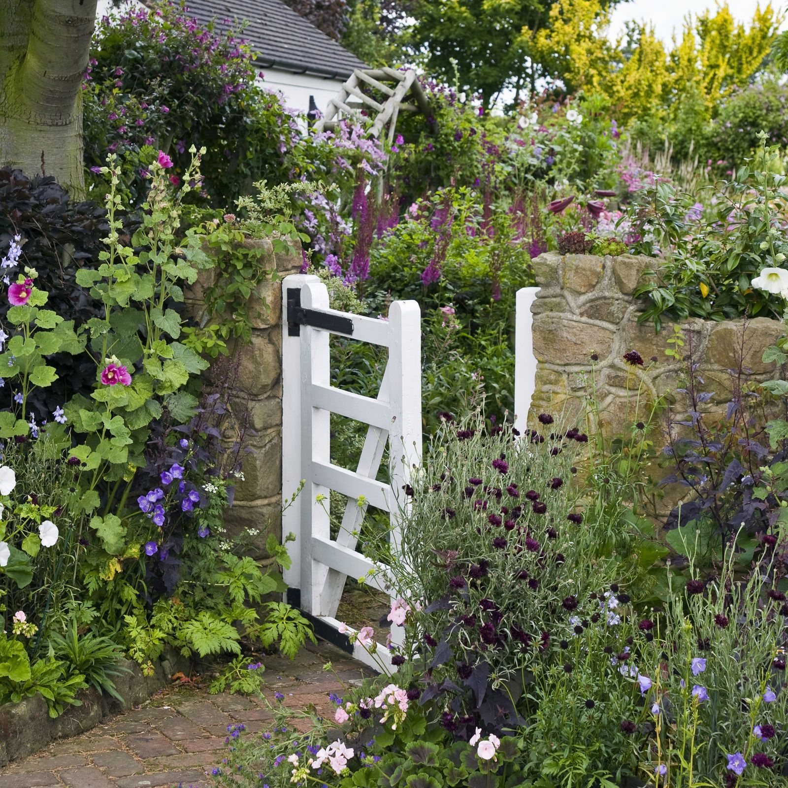 The secret to a cottage-style garden is to create an informal yet inviting landscape through overflowing flowerbeds of varying