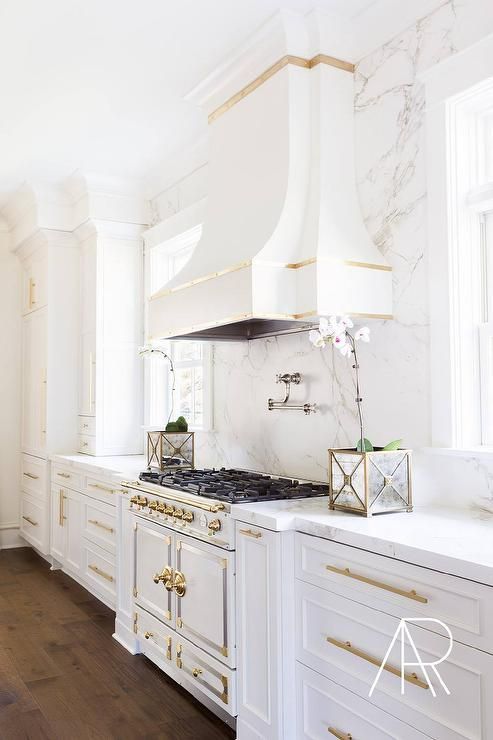 White and gold kitchen features white cabinets adorned with long gold pulls paired with Silestone countertops and backsplash that